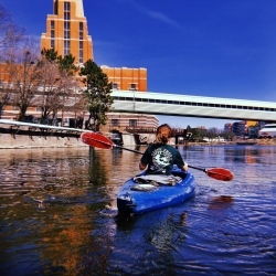 a kayaker on the grand river with the accident fund building in the background