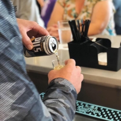 bartender pouring an LBC Peninsula Pilsner Beer from a can into a cup