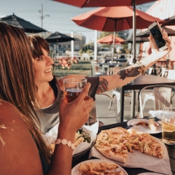 Two friends take a selfie while eating pizza and drinking beer at Lansing Brewing Company.